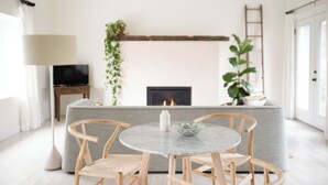 Ein modernes Wohnzimmer mit Kamin, einem runden Tisch mit Stühlen, einer Couch und einem Fernseher.