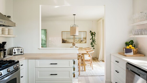 A modern kitchen with white cabinetry, a gas stove, and a dining area with wooden chairs and a table. - The Addison | Modern Farmhouse | Pool  and  Hot Tub (Prince Edward)