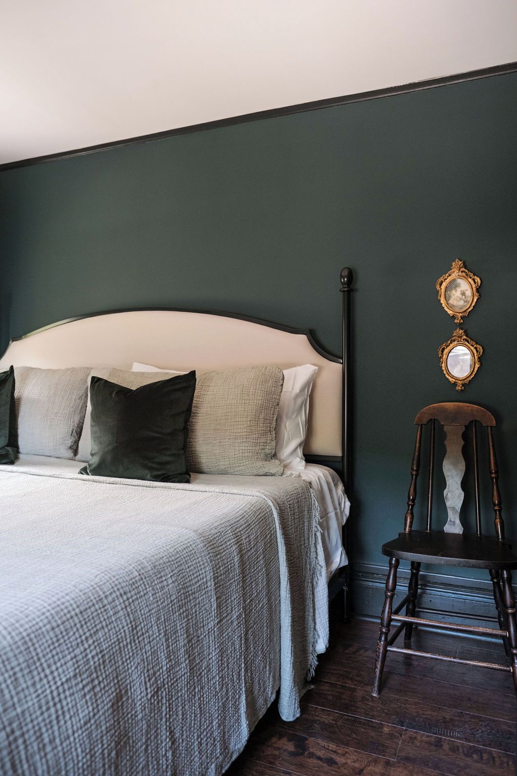 A bedroom with a bed, pillows, a chair, and two wall-mounted mirrors.