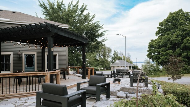 Un espace extérieur aménagé en terrasse, avec un sol en pierre, une plateforme en bois et des sièges d’extérieur.