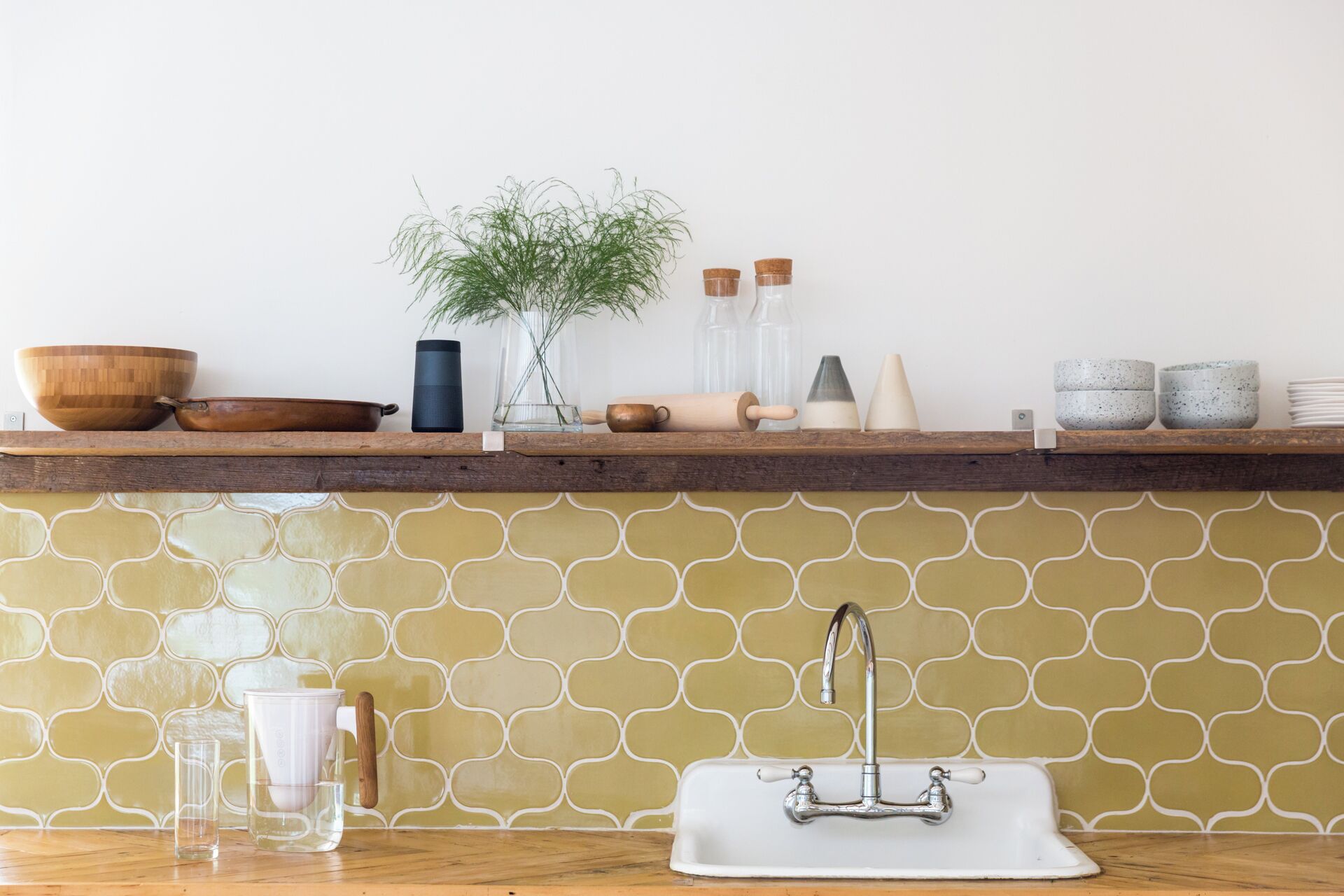 Een keuken met een houten aanrecht, een spoelbak en een spatwand met een geometrisch patroon.