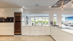 A modern kitchen with a central island, built-in appliances, and large windows offering a view of the outdoors. - SoFloasis - Home w/ Heated Pool, close to beaches (Lighthouse Point)