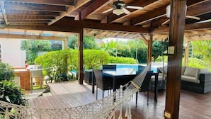 A covered outdoor area with a hammock, seating, and a pool. - Urban Paradise (San Juan)