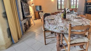 Een rustieke eethoek met een stenen openhaard, een houten eettafel en stoelen.