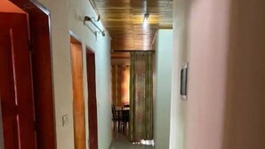 Un couloir doté d’un sol carrelé, d’un plafond en bois et d’une porte située sur le côté gauche.