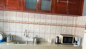 Une cuisine avec des meubles de rangement en bois, un pare-feu en carrelage, un évier, une cuisinière et un four à micro-ondes.