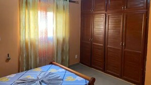 Une chambre à coucher avec un lit, une armoire en bois et une fenêtre avec des rideaux.