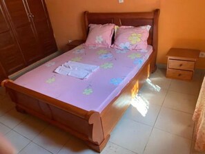 Cozy retreat with a single bed, floral-patterned bedspread, and a nightstand with a drawer.