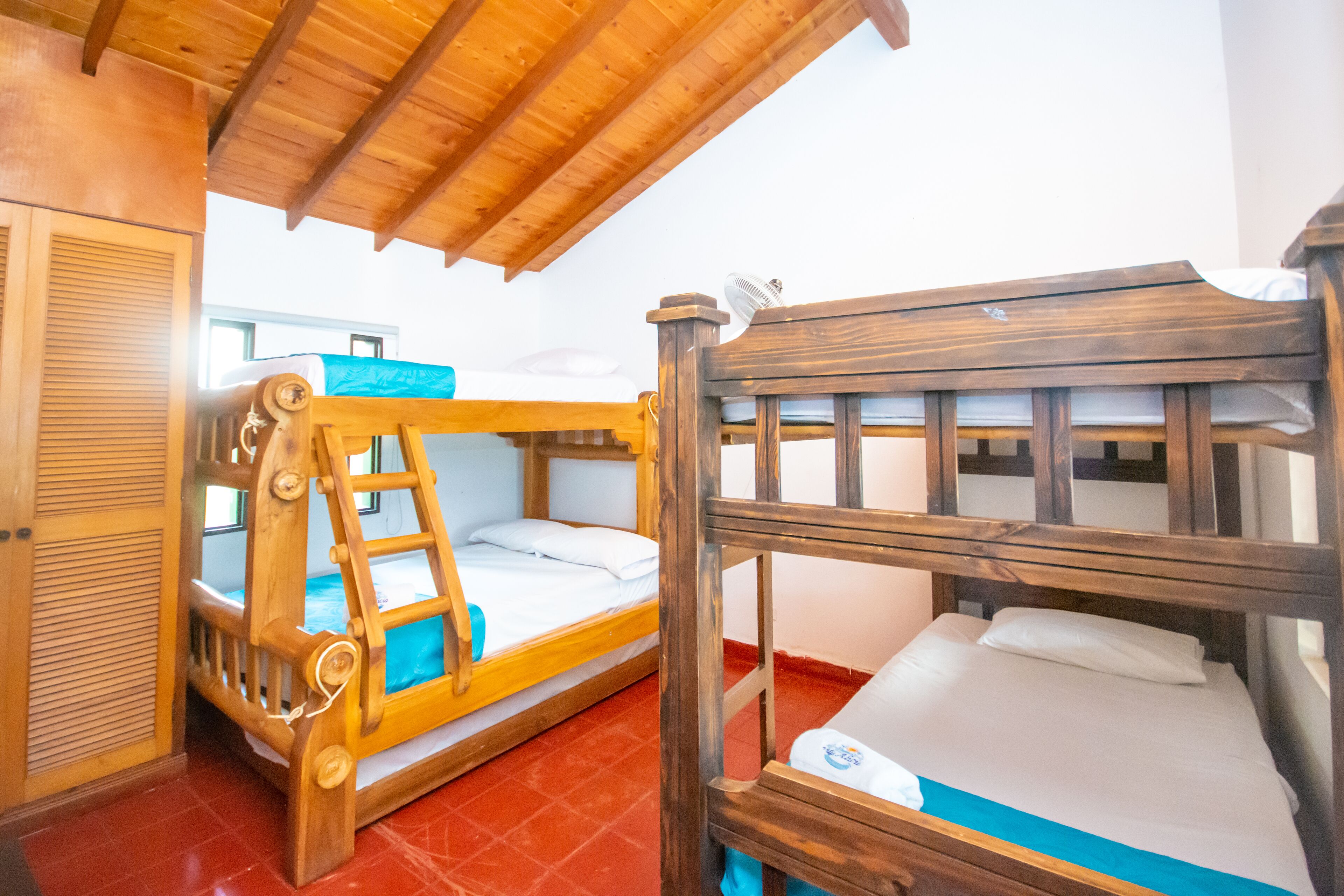 A room with two bunk beds, wooden furniture, and a tiled floor.