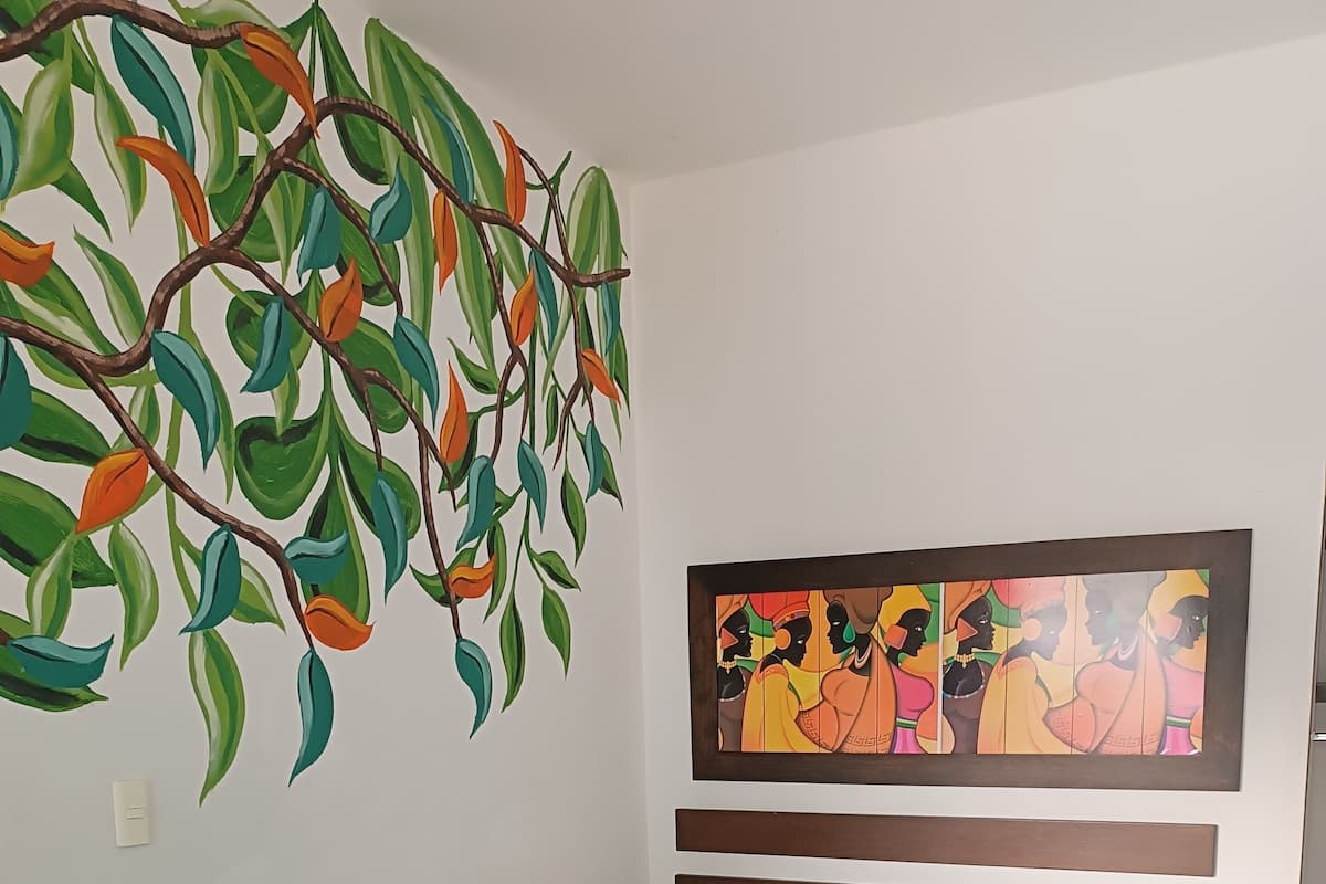 A hotel room with a bed, a wall mural, and a tiled floor.