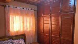 Une chambre à coucher avec un lit, une armoire en bois et une fenêtre avec des rideaux.