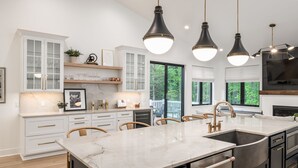 Een moderne keuken met witte kastjes, een marmeren aanrecht en hanglampen.