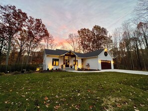 A two-story house with a garage, surrounded by a lawn and trees. - Fall Retreat | Hot Tub, Games & Wine Country (South Haven)