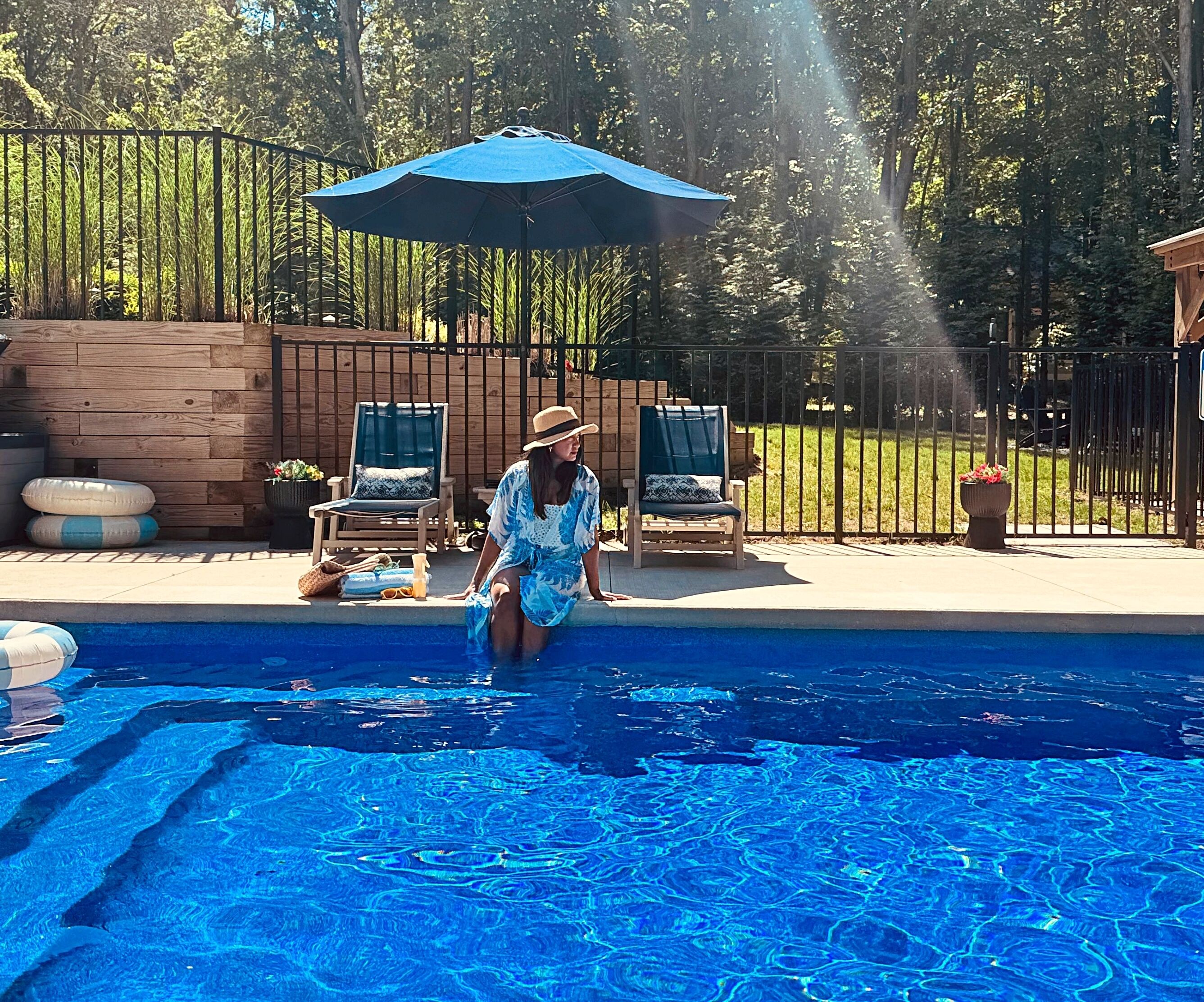 En swimmingpool med liggestole og en parasol.