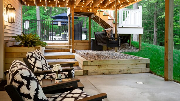 Une terrasse extérieure avec des meubles en bois, un foyer et une vue sur le jardin.