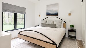 A bedroom with a bed, a window, a chandelier, and a painting on the wall. - Fall Retreat | Hot Tub, Games & Wine Country (South Haven)
