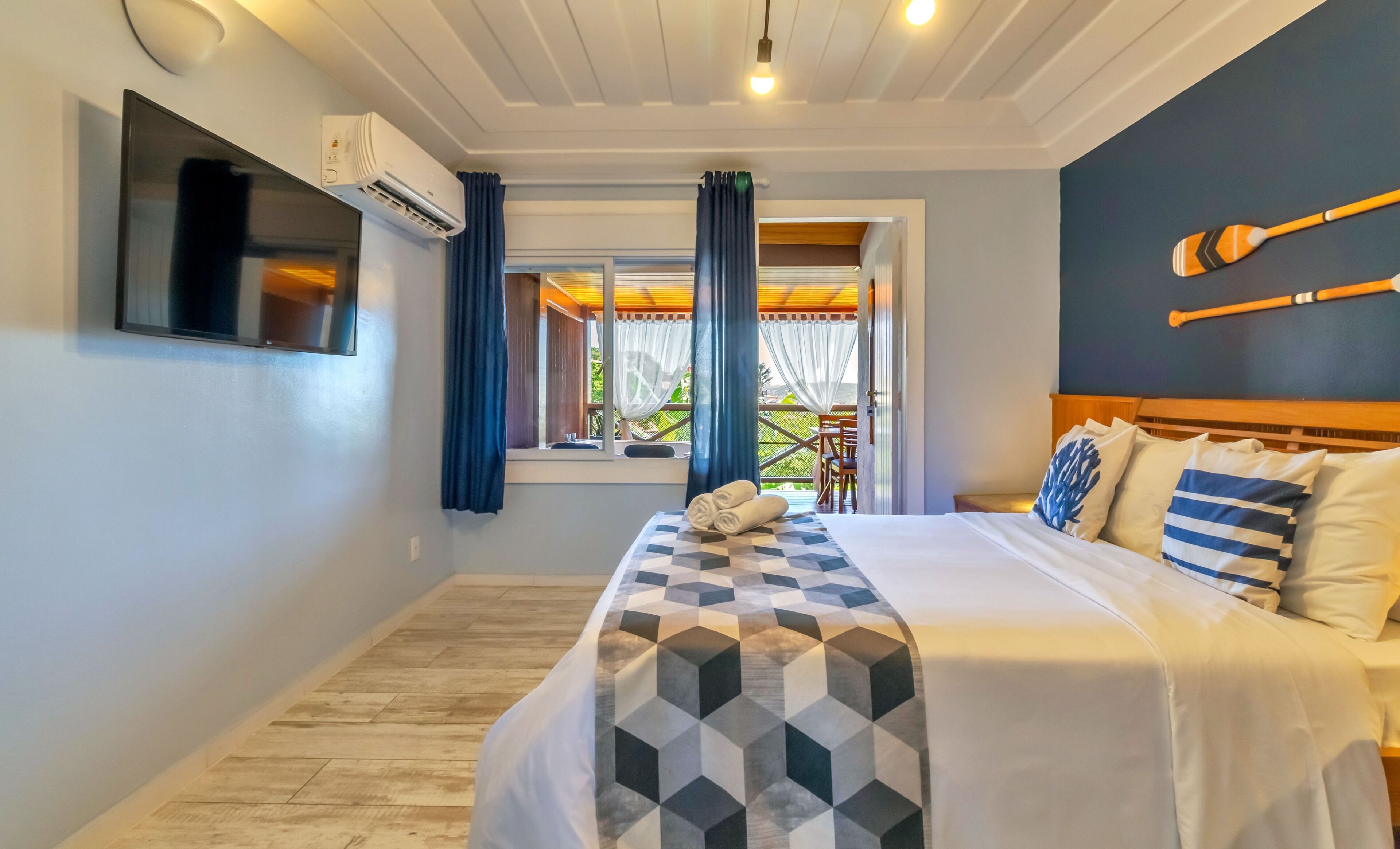 A bedroom with a bed, a TV, an air conditioner, and a view of the outdoors.