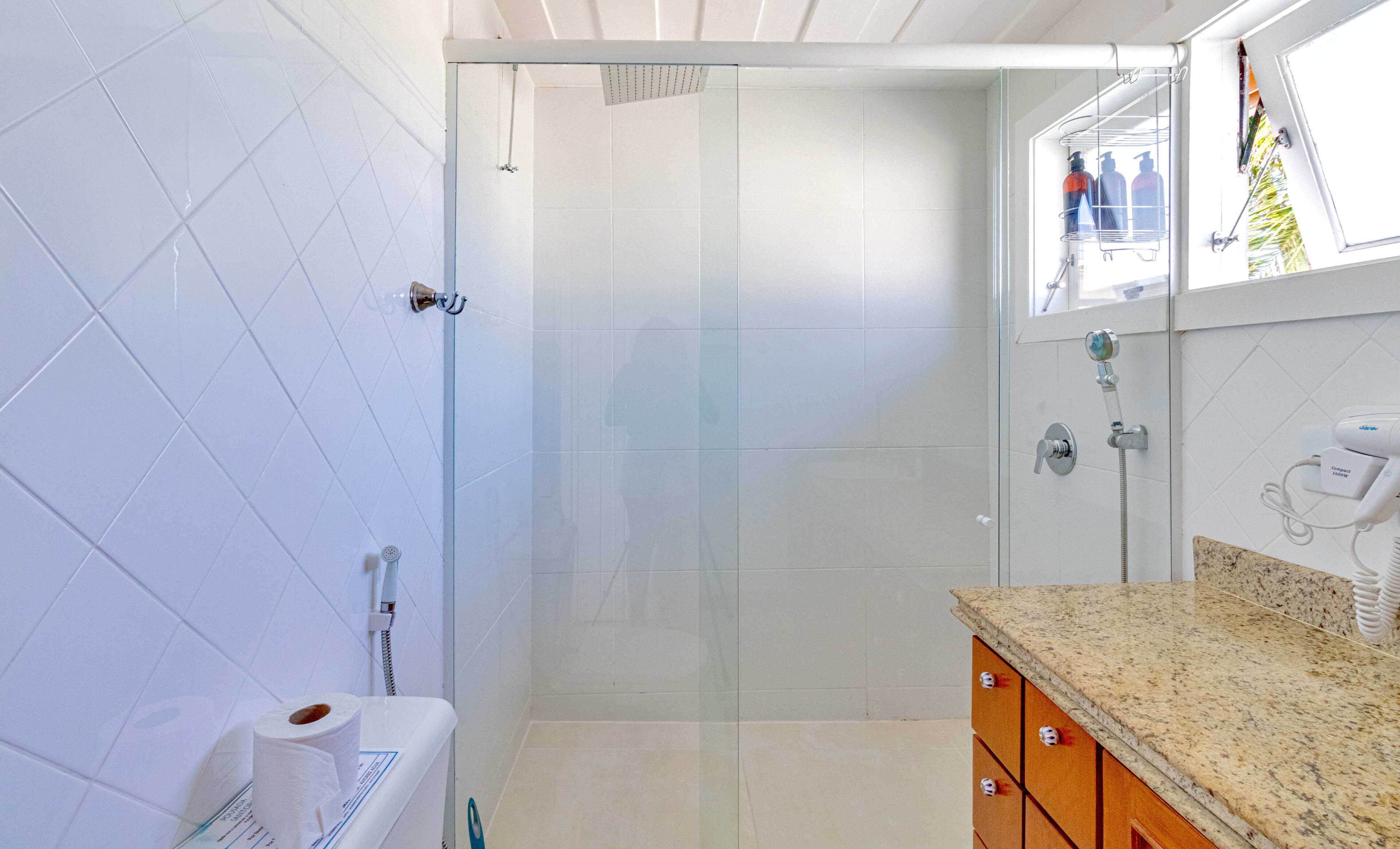 A bathroom with a glass shower door, a toilet, and a sink with a granite countertop.