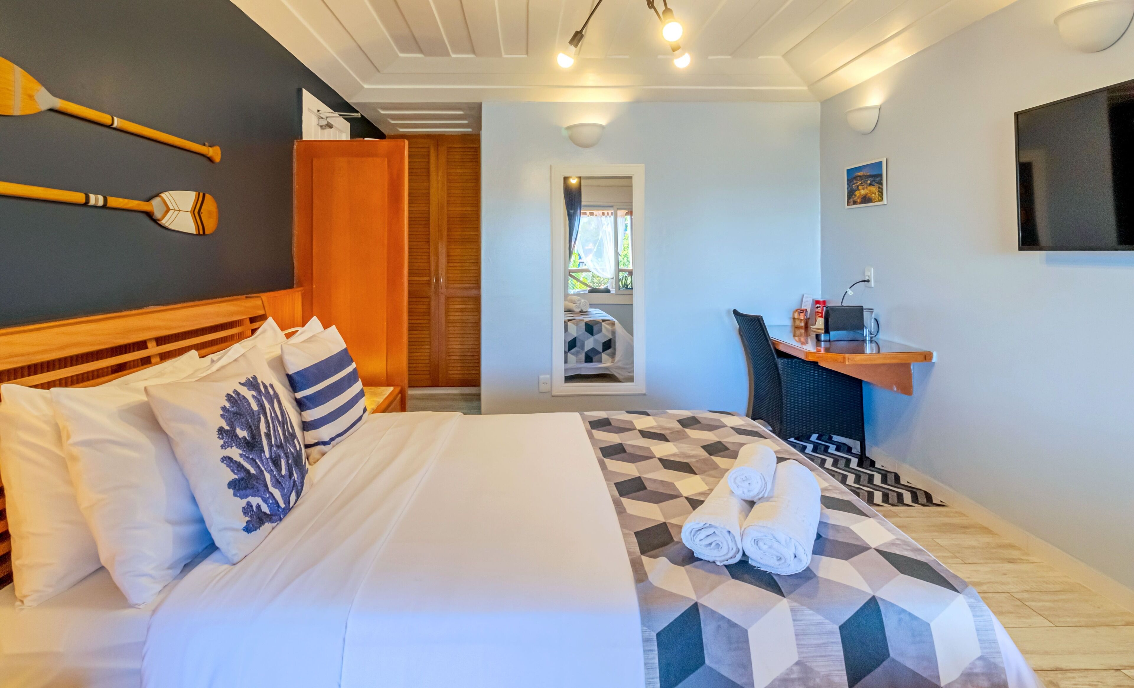 Ein Hotelzimmer mit Bett, Schreibtisch, Fernseher und Blick ins Freie.