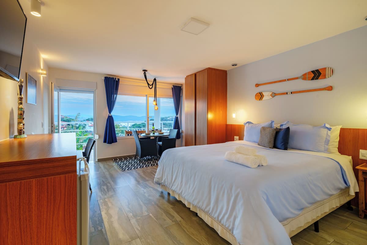 A hotel room with a large bed, a desk, and a view of the city.