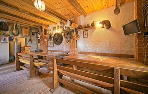 A rustic interior with a wooden table, benches, and various kitchen utensils hanging on the wall. - Cozy home in Prodin Dol (Prodin Dol)
