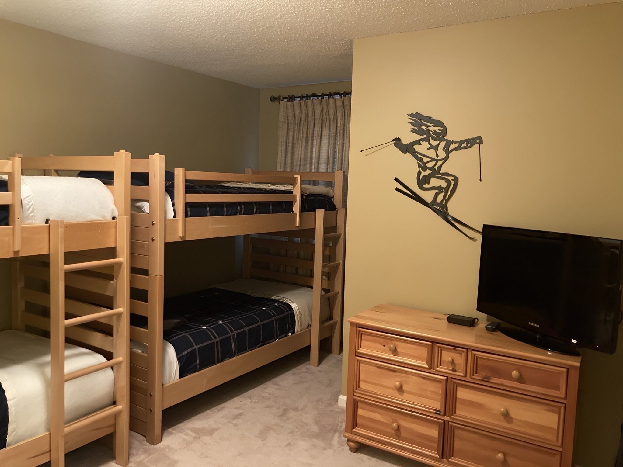 A bunk bed room with a TV and dresser.