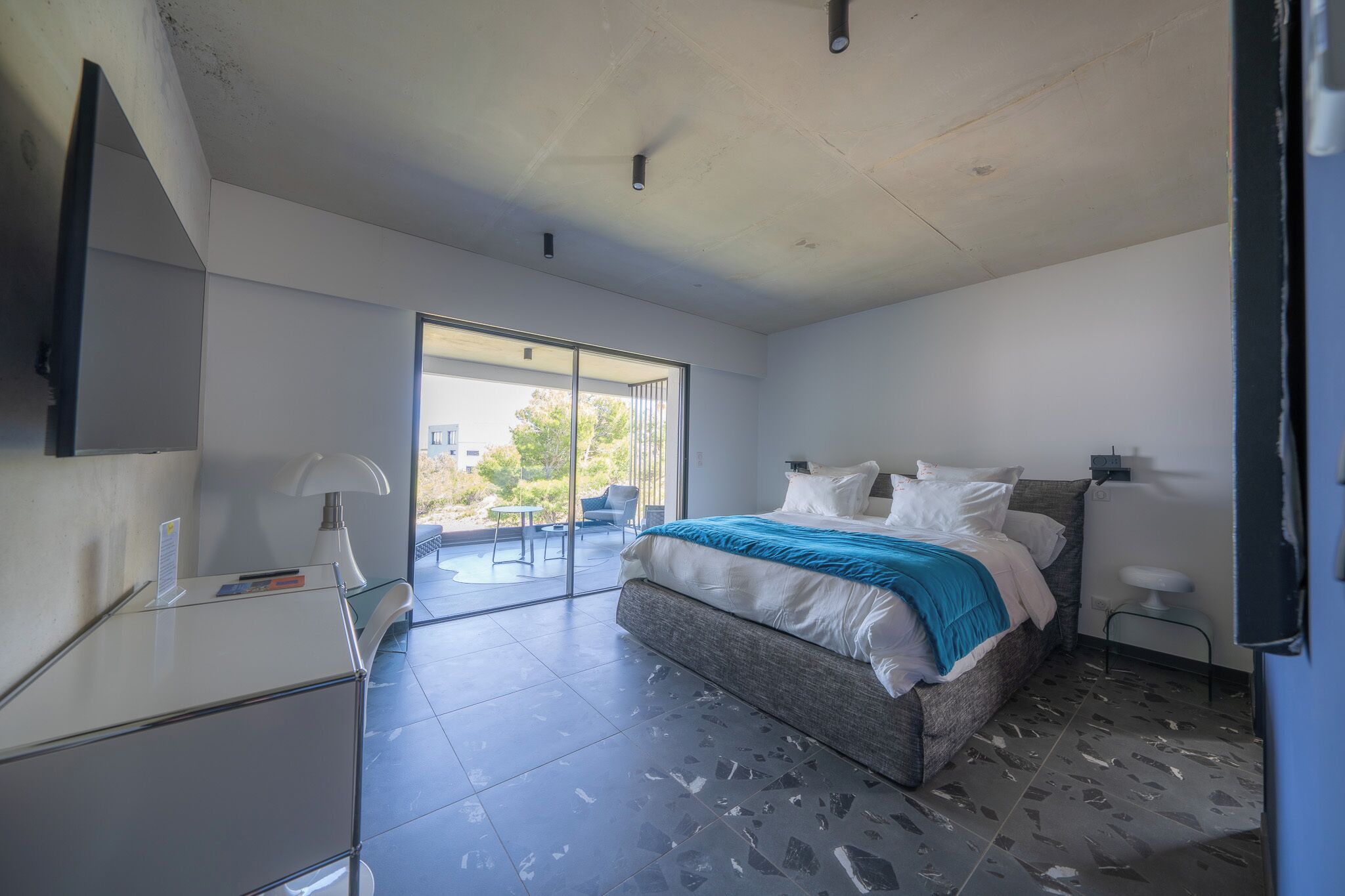 A modern bedroom with a large bed, a desk, and a chair.