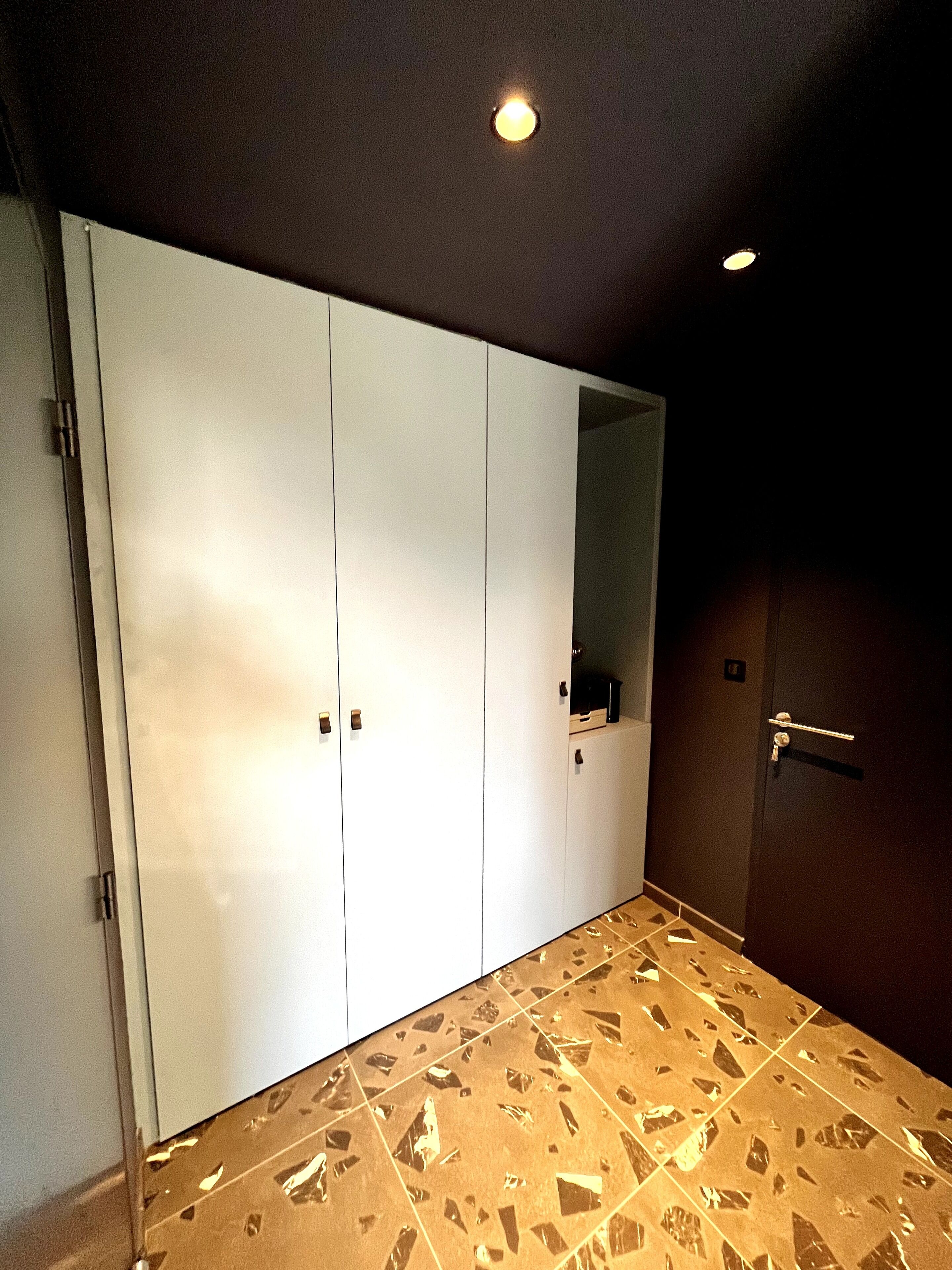 A room with a large wardrobe, a mirror, and a patterned floor.