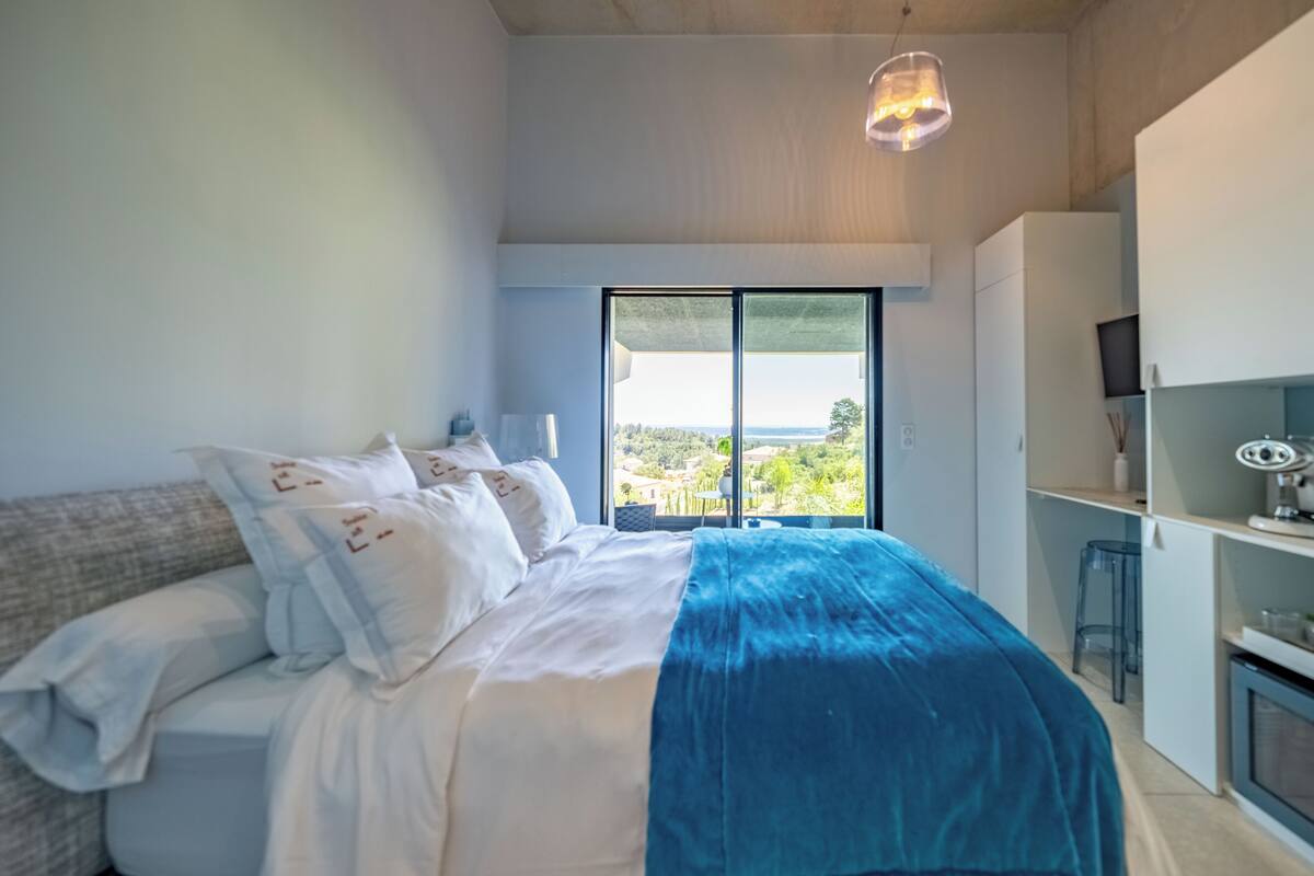 Un dormitorio con cama, escritorio y vistas al exterior.