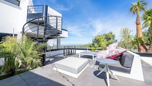 A rooftop patio with a spiral staircase, outdoor furniture, and a view of the ocean. - SUITE 28 (Treilles)