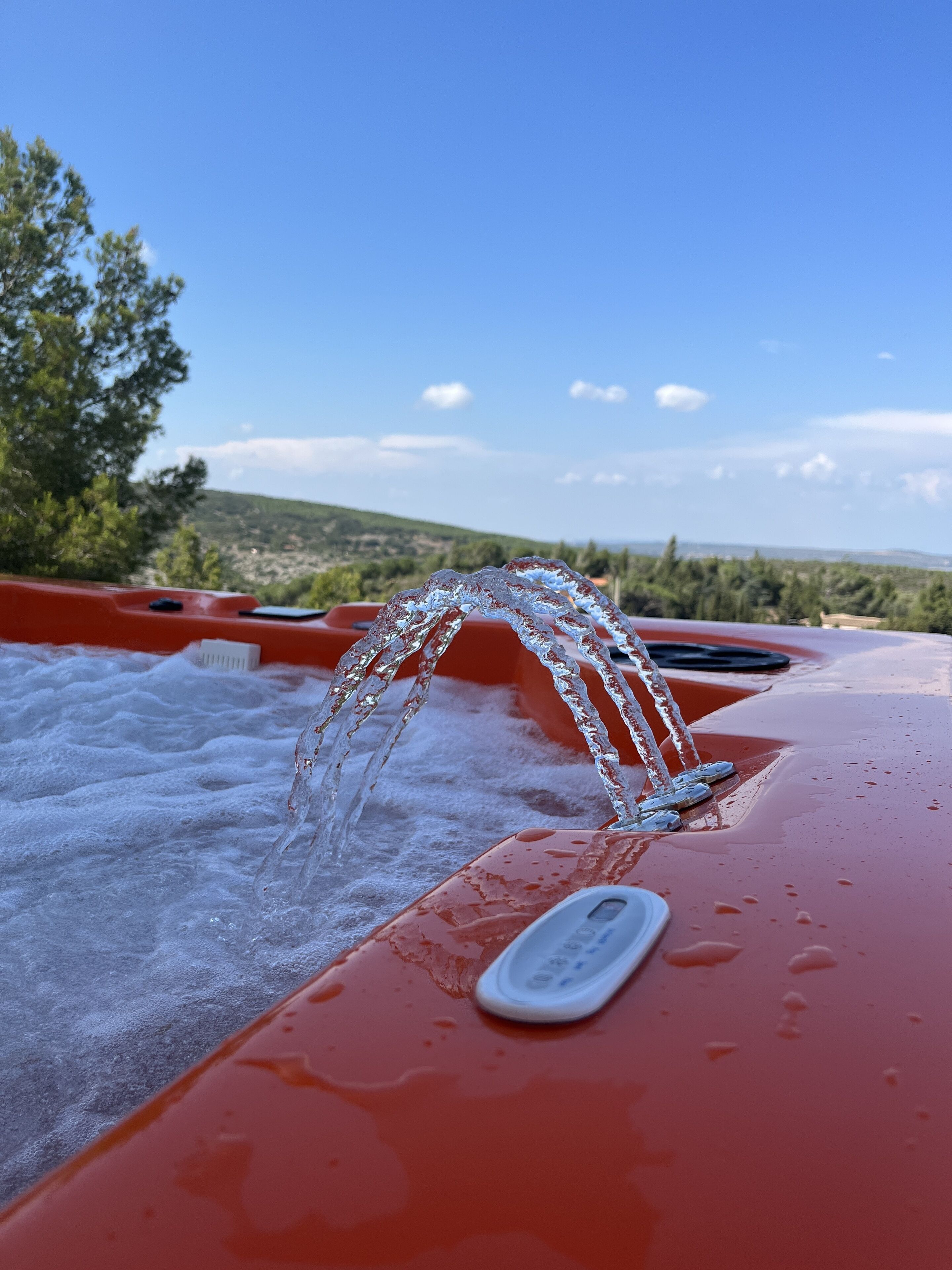 A hot tub with water flowing out, surrounded by a red tub and a clear sky.