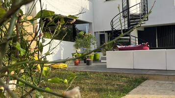 Un edificio moderno con fachada blanca, una escalera en espiral y plantas en macetas al frente.