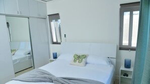 Un dormitorio con cama, armario, mesita de noche y ventana con cortinas.