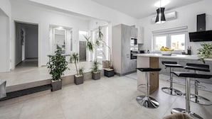 Une cuisine moderne dotée d’un îlot central, de tabourets de bar et de plantes en pot.