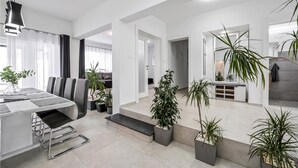 Un espace de vie moderne comprenant un coin repas, un canapé et de nombreuses plantes en pot.
