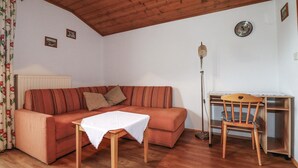 Una sala de estar acogedora con un sofá, una mesita, una silla de madera, una lámpara de pie y un radiador.