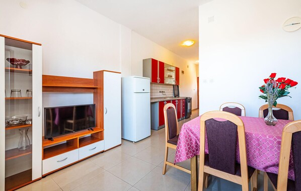 A compact kitchen with a built-in TV, a refrigerator, and red cabinets.