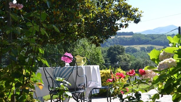 An outdoor dining area with a table and chairs, surrounded by lush greenery and flowers. - GURE GOSTUAN - ITXASSOU (ITXASSOU)