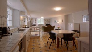A compact kitchen with a dining area, featuring a tiled floor, a built-in stove, and a dining table with chairs. - GURE GOSTUAN - ITXASSOU (ITXASSOU)