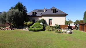 Une maison à deux étages, dotée d’un toit en pente, d’un petit porche à l’avant et d’une pelouse bien entretenue.