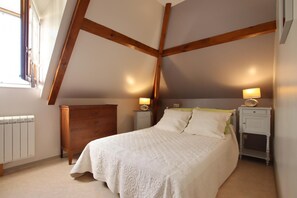 Cozy bedroom with a large bed, wooden dresser, and two bedside tables.
