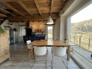 A spacious kitchen with a wooden ceiling, a dining area with a large table and white chairs, and a view of a mountainous landscape through a large window. - UTHURRALTIA - LARRAU (LARRAU)
