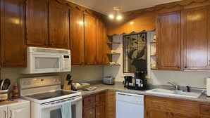 A kitchen with wooden cabinets, a white microwave, a stove, a dishwasher, and a coffee maker.