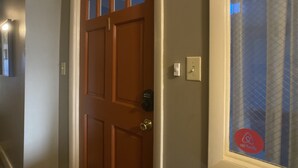 A wooden door with a glass panel and a doorbell.