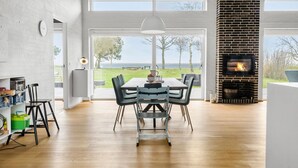 Ein stilvolles Esszimmer mit großem Tisch und Stühlen, Kamin und Blick ins Freie.
