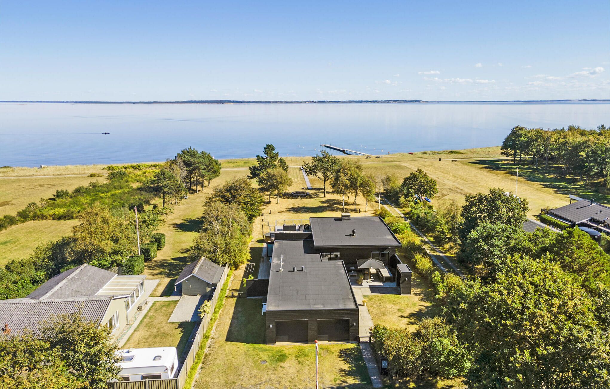 A residential area with houses, a grassy field, and a body of water in the background.