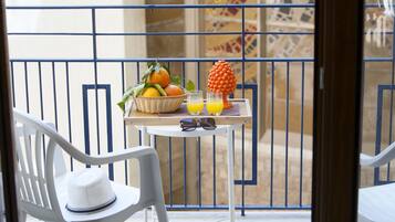 Un balcone con un tavolo apparecchiato con frutta, bicchieri e un cappello.