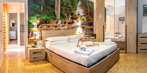 Ein Schlafzimmer mit einem großen Bett, einem Holz-Kopfteil, Nachttischen, einem Beistelltisch, einem Spiegel und einem Wandbild mit einem Wasserfall.