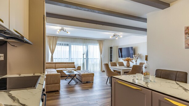 A modern living room with a sofa, coffee table, and dining area with chairs and a TV. - 4 bedroom lovely apartment in Medulin (Medulin)