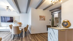 A modern kitchen with a marble countertop, a dining area with chairs, and a TV mounted on the wall. - 4 bedroom lovely apartment in Medulin (Medulin)